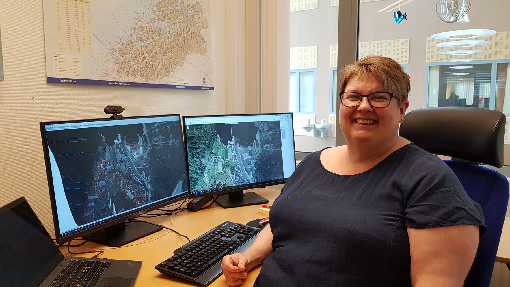 Turid Elde hos Kartverket sitter foran pc-skjermer med historiske kart på.