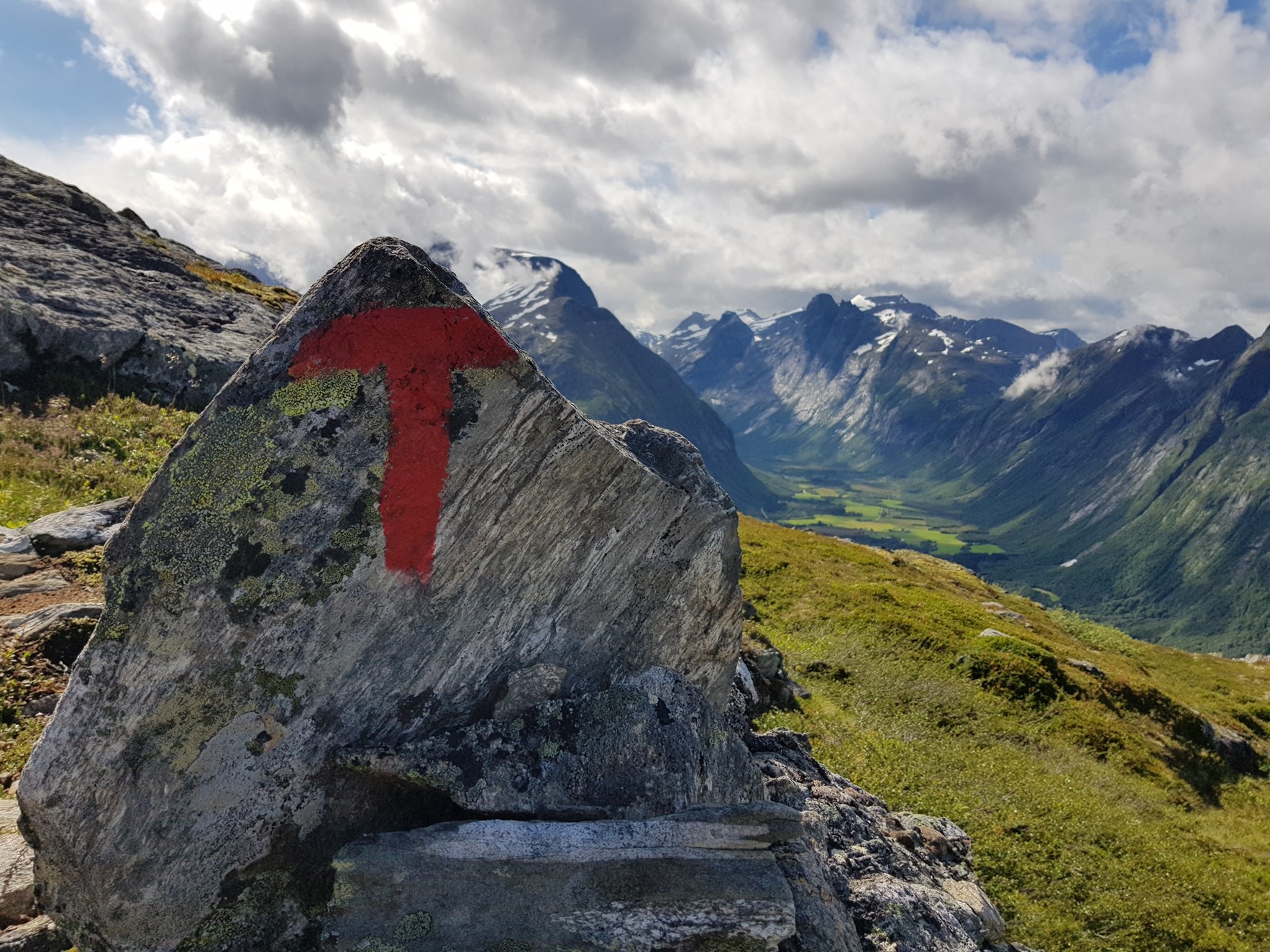 N&aelig;rbilde av r&oslash;d t-merking, med dalf&oslash;re og spisse tinder i bakgrunnen.