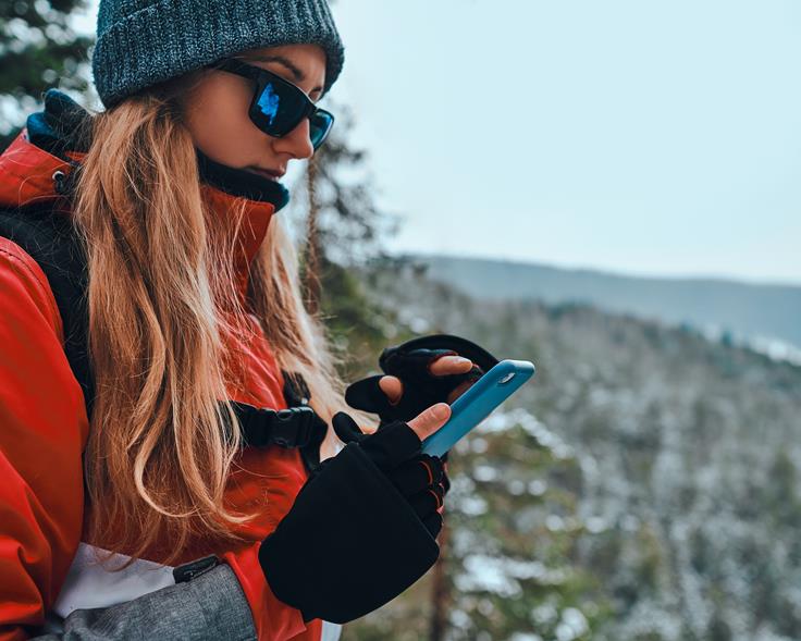 Kvinne på vintertur med Hvor?-appen oppe på telefonen