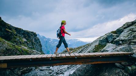 Kvinne går over bro i fjellet