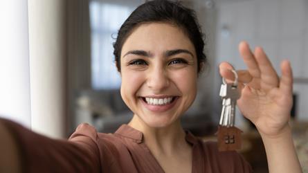 Smilende dame viser nøkler til ny bolig. Foto: Mostphotos