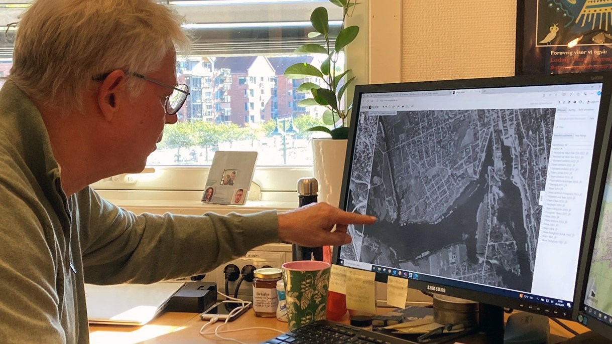 Sigurd Laland peker på et historisk flyfoto på en PC-skjerm.