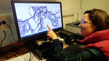 Havforsker Katherine Dunlop peker på  dataskjerm som viser marine grunnkart. Foto.