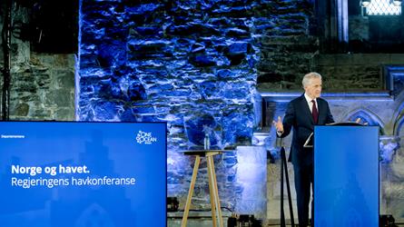 Stasminister Jonas Gahr Støre står ved en blå talerstol og snakker på regjeringens havkonferansen i 2023. Foto: Paul S. Amundsen/Klima- og miljødepartementet