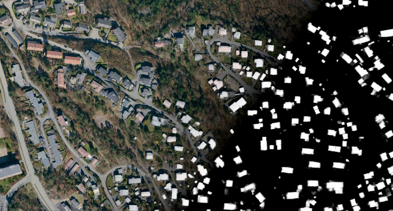 Flyfoto som viser store og sm&aring; bygninger i terrenget. 
