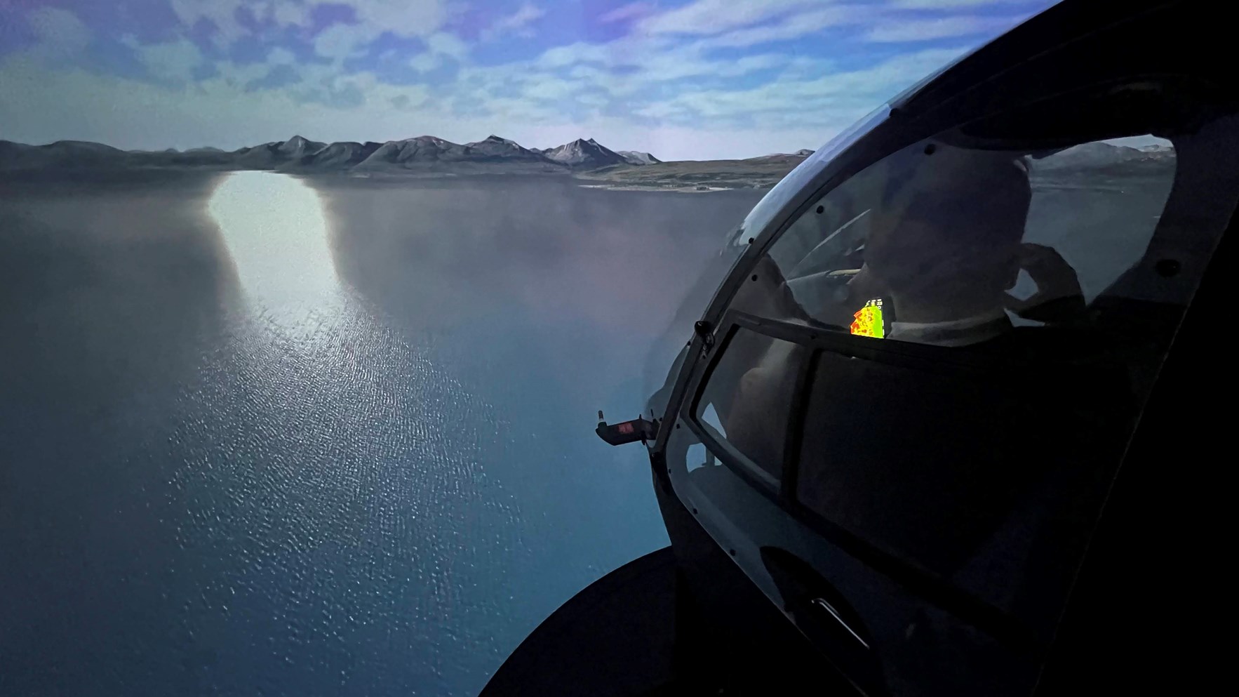 Dataanimert bilde av Norsk luftambulanses helikoptersimulator som flyr over en fjord i motlys.