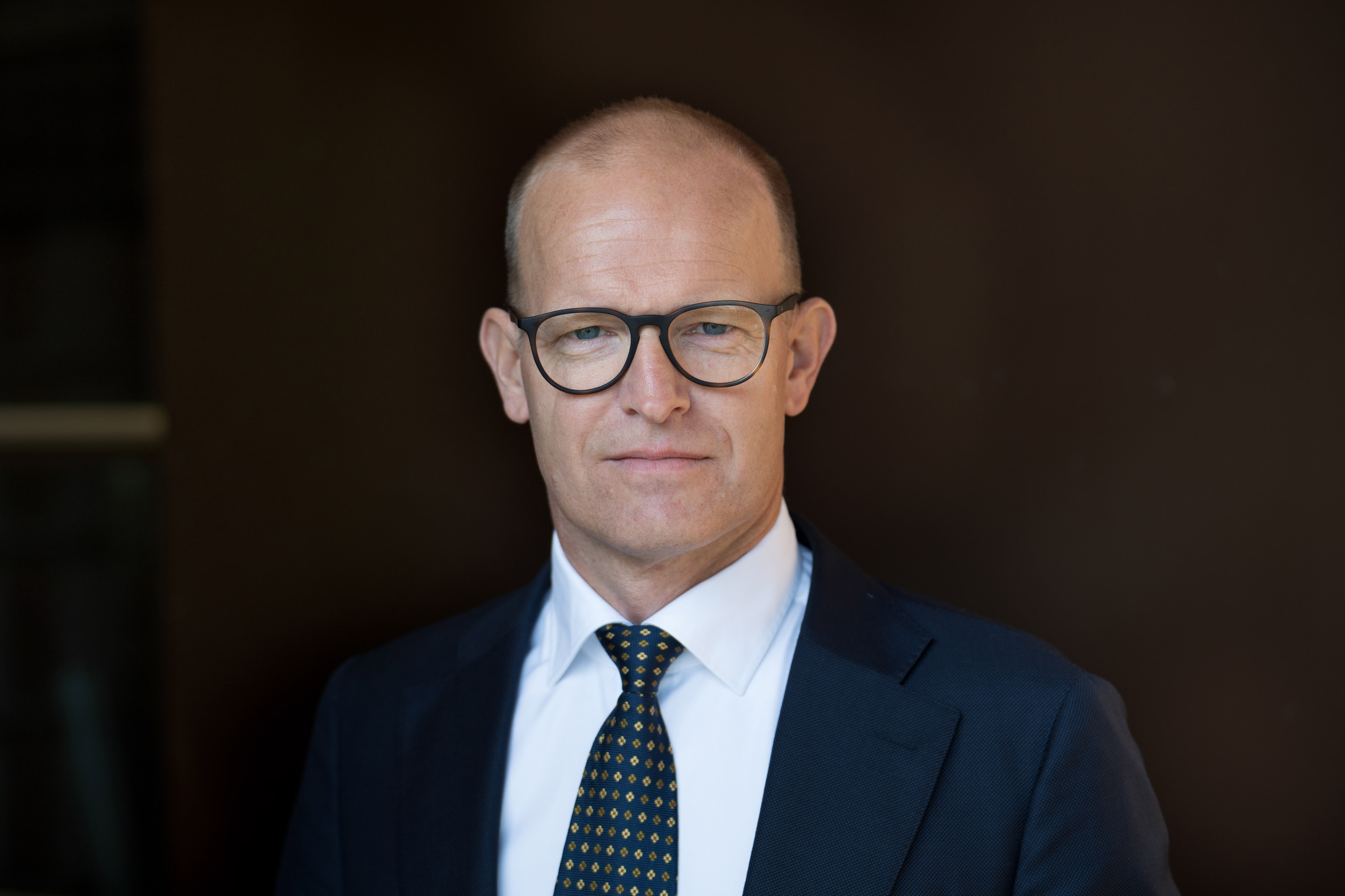 Kartverkssjef Johnny Welle, en mann i dress fotografert mot en m&oslash;rk bakgrunn.