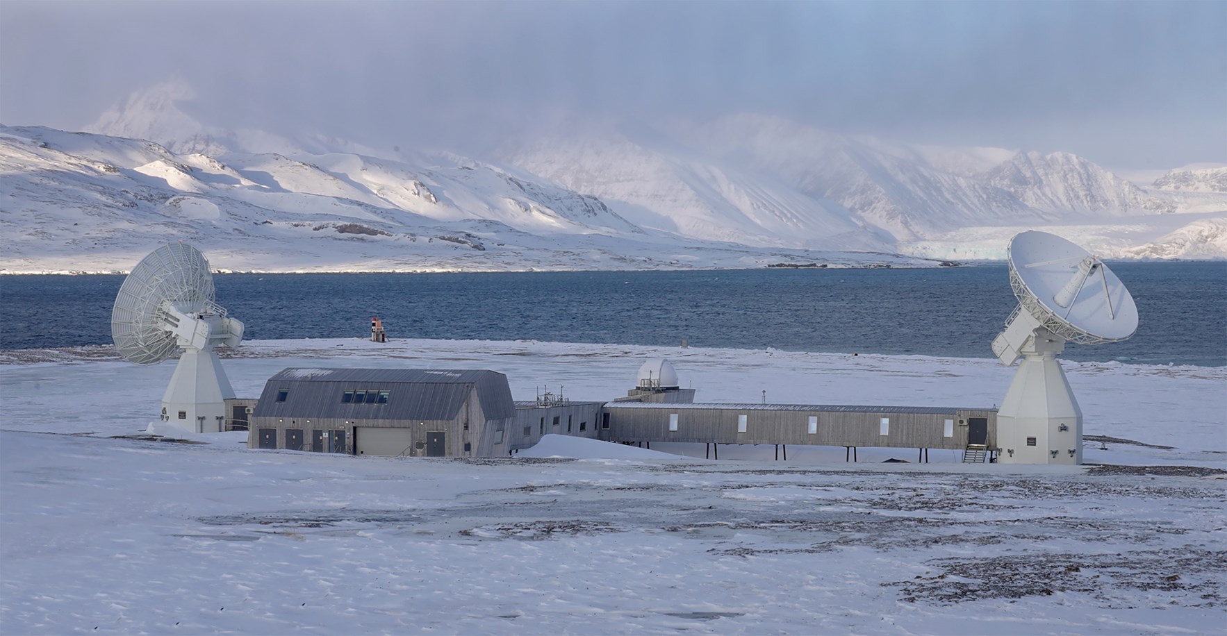 Jordobservatoriet i Ny-Ålesund på Svalbard med med satelittmottakere og arktisk landskap i bakgrunnen.