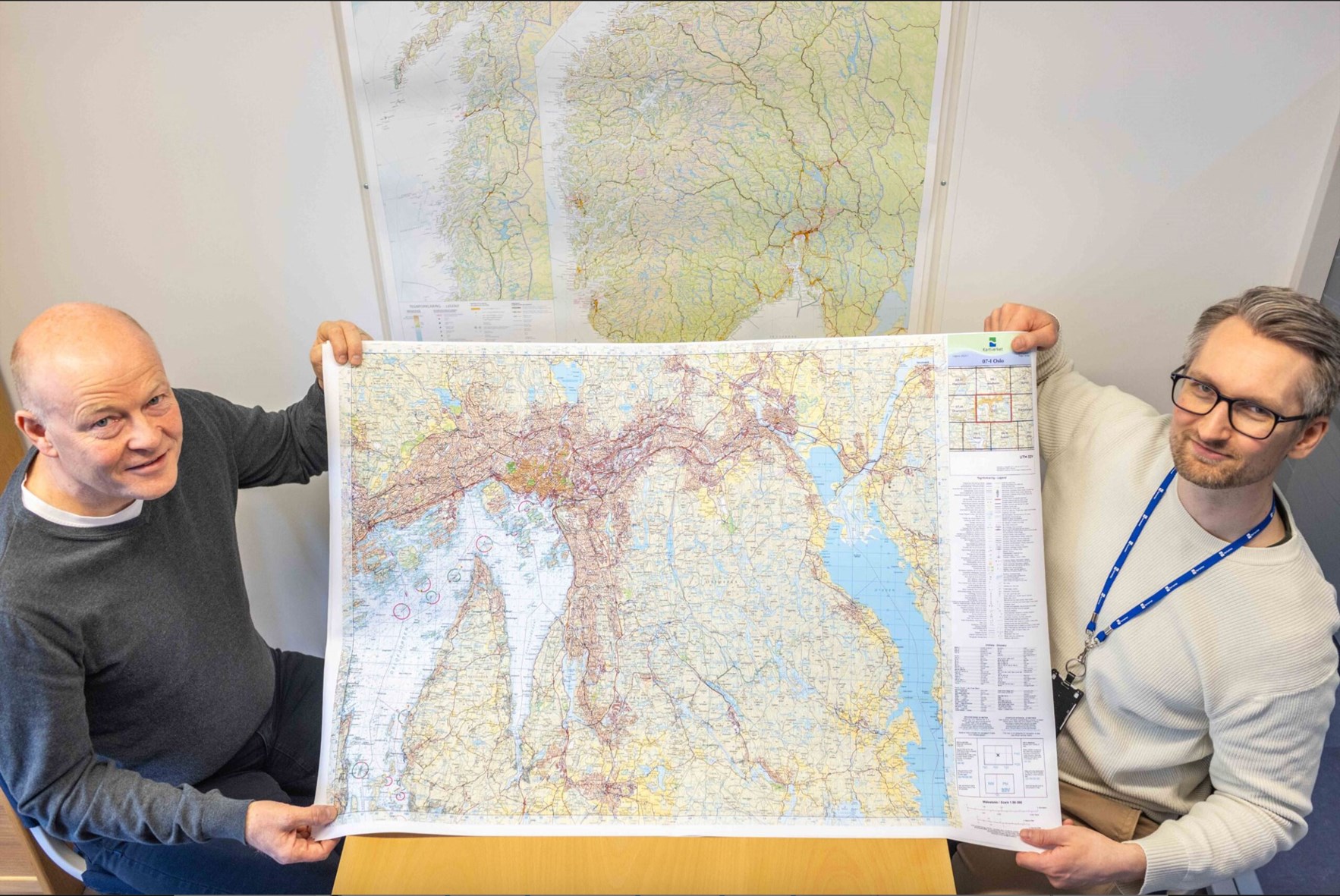 To mannlige Kartverks-ansatte holder et turkart Norge 1:50 000 mellom seg