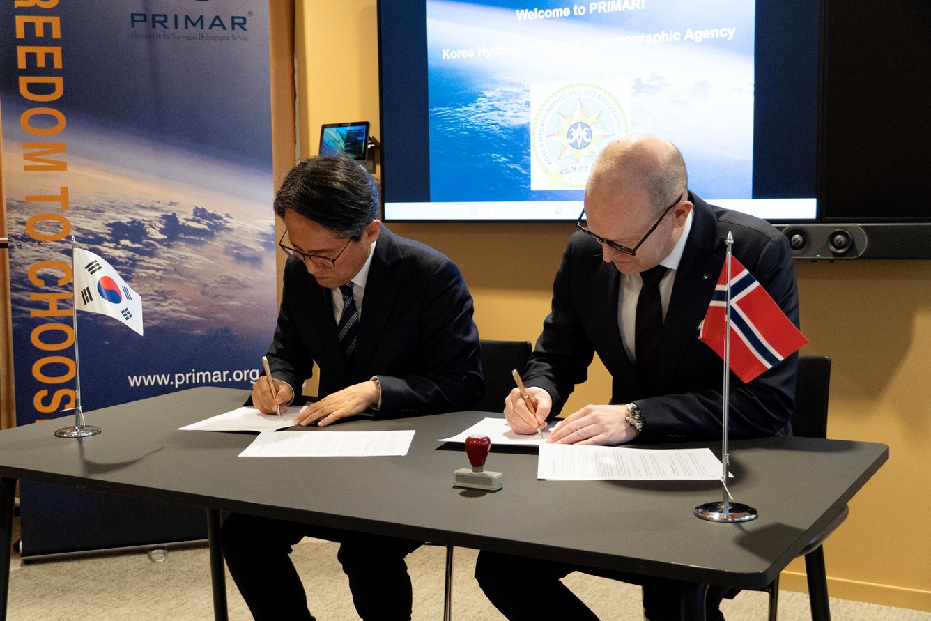 Kyusam Jung og Johnny Welle signerer en bilateral avtale. De sitter ved et bord pyntet med det s&oslash;r-koreanske og norske flagget.