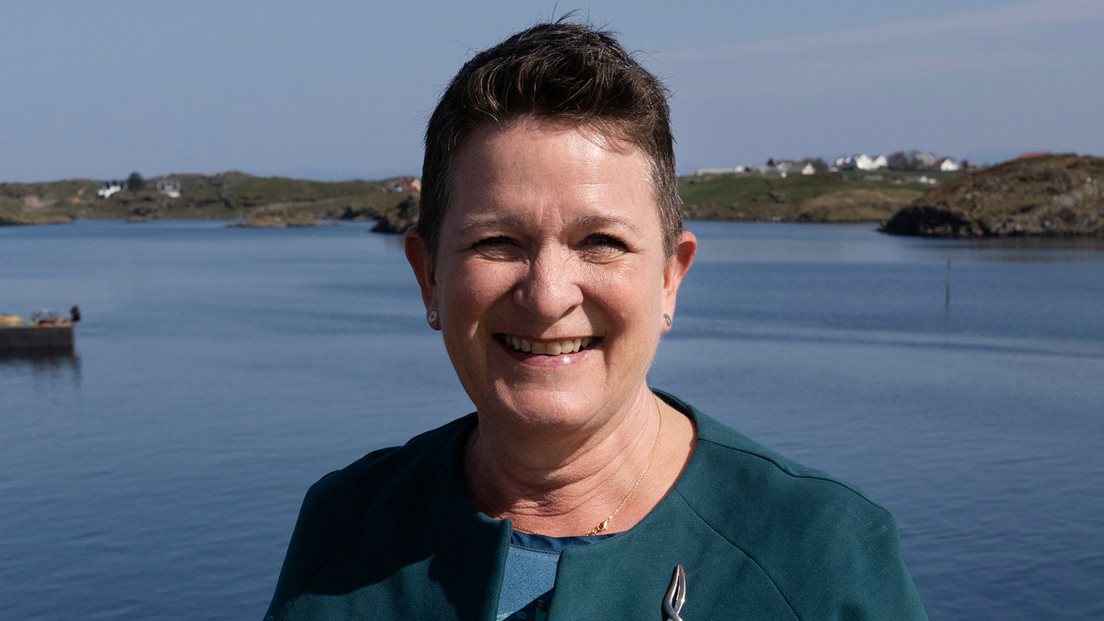 Birte Noer Borrevik med kystlandskap badet i sol i bakgunnen. Foto: Marie von Krogh, Kartverket