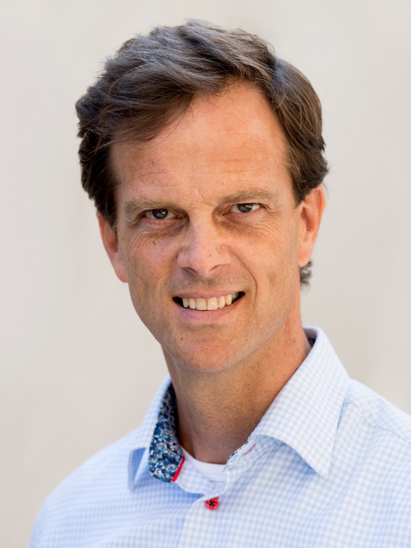Mann i skjorte smiler mot kamera.