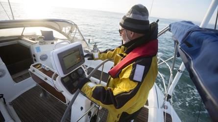 Mann om bord på en seilbåt sjekker elektronisk sjøkart i sin kartplotter. Foto: AdobeStock