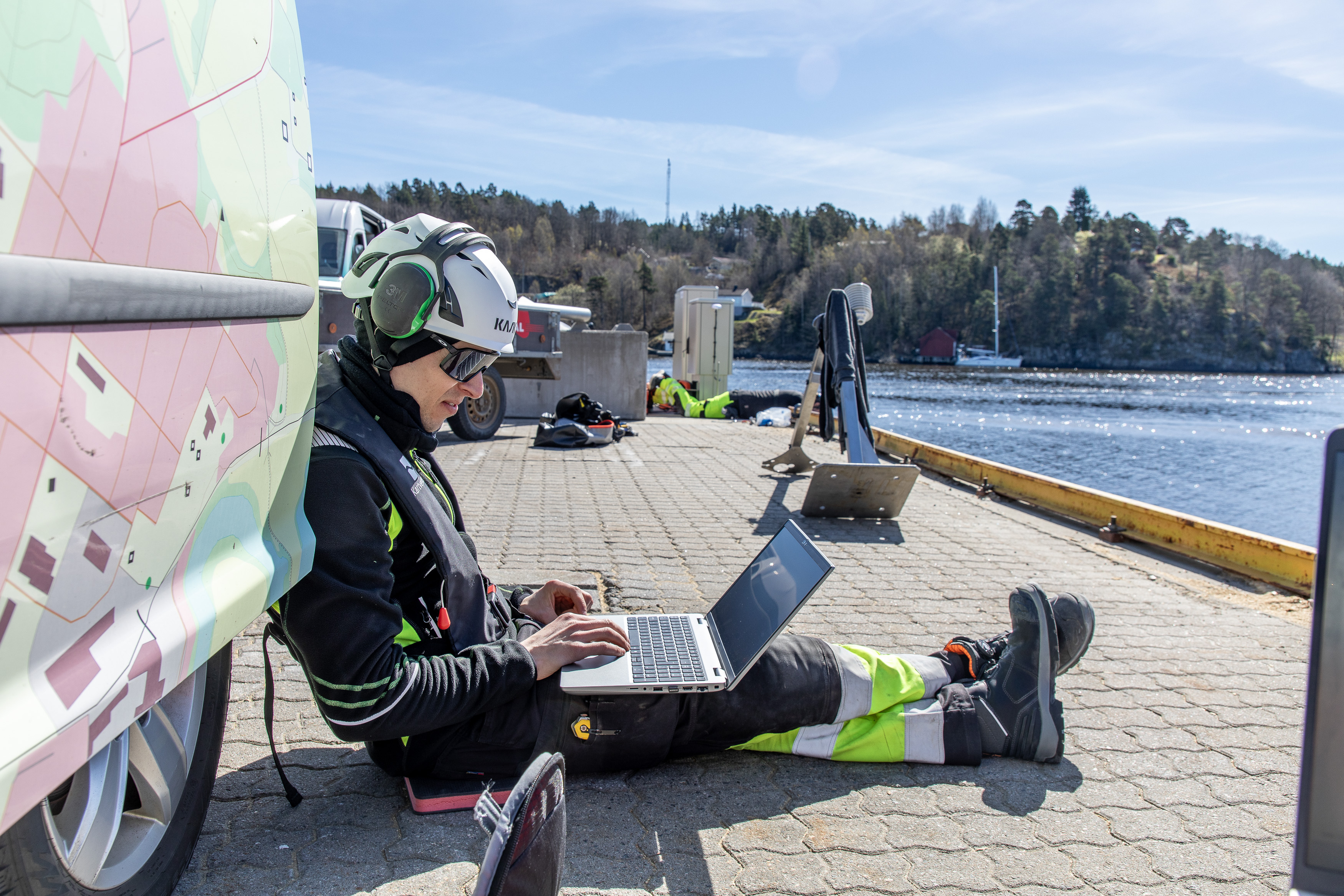 En mont&oslash;r sitter p&aring; bakken med ryggen lent mot bilen, mens han sjekker tekniske m&aring;linger p&aring; en PC.
