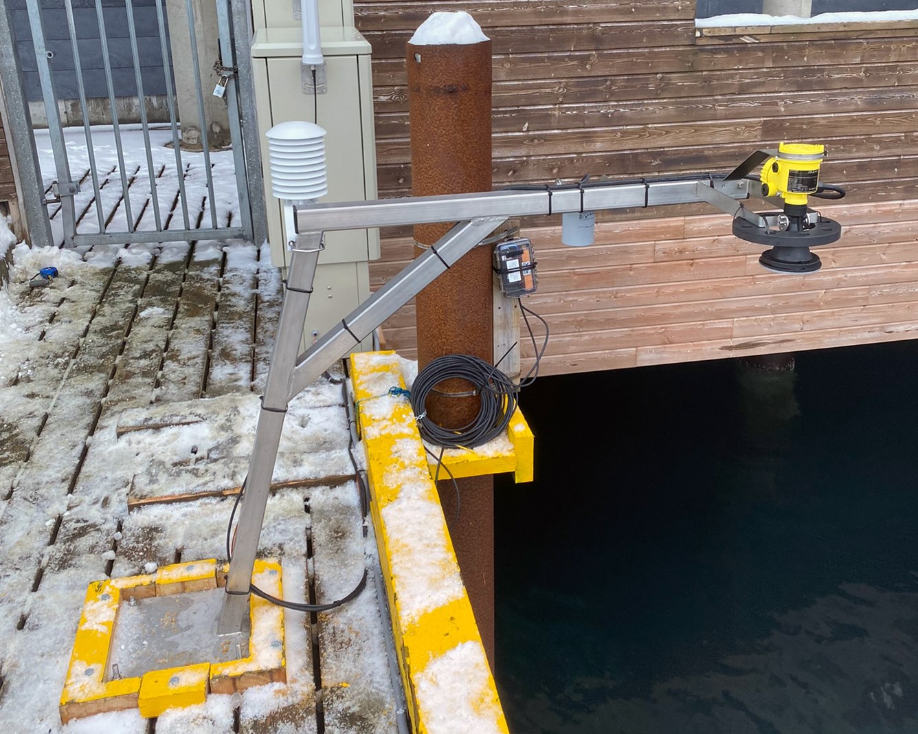 En vannstandsmåler, radarmåler, er montert på ei kai. Det er litt snø og is på kaia.