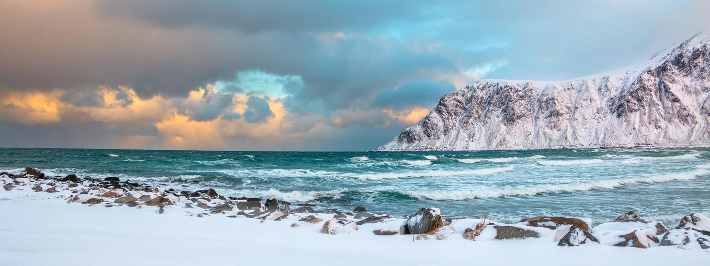 Vintermorgen på en strand i Lofoten. Det er lavvann og bølger slår mot land. Foto: Gooman/Mostphotos