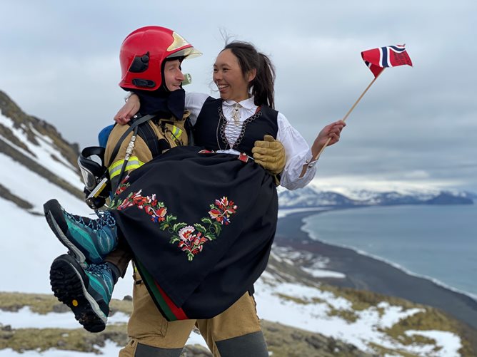 Sigmund Lønnve med hjelm løfter Silje Grøslie Wennesland i bunad.