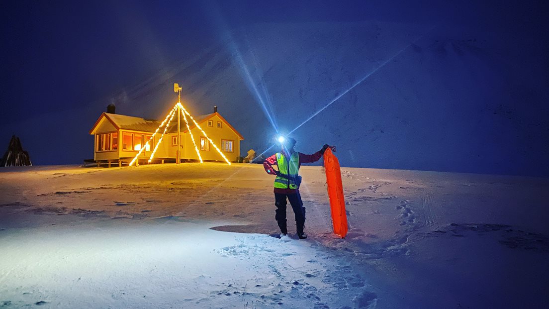 Person med hodelykt utafor hytte i Todalen, Svalbard